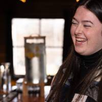 Woman attending event with black, white, and gray sweater on, smiling
